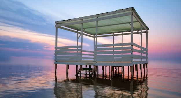 Photo bright sunset, and a bungalow on the water.