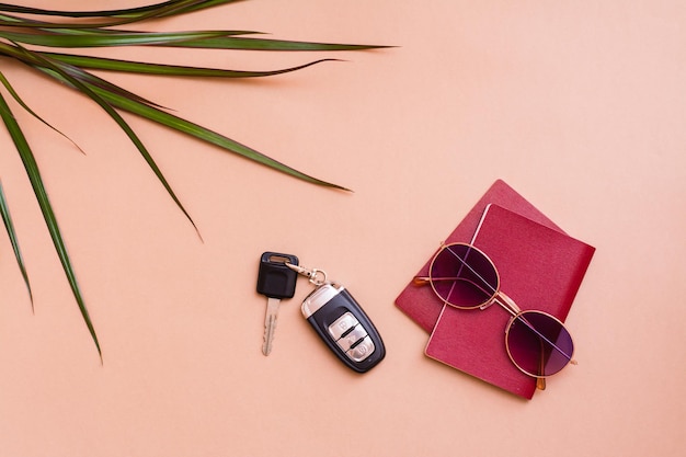 Bright travel flat lay with sunglasses, passports, palm leaves and car keys on a beige background. Car travel. Top view