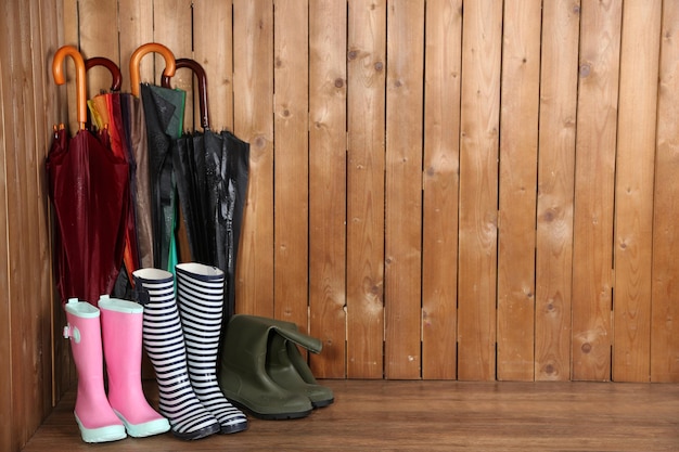 Bright umbrellas leaning against a wooden wall and gumboots