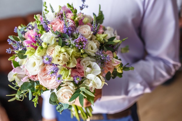 Bright wedding bouquet of summer white pink roses and orchid\
with violet wildflowers