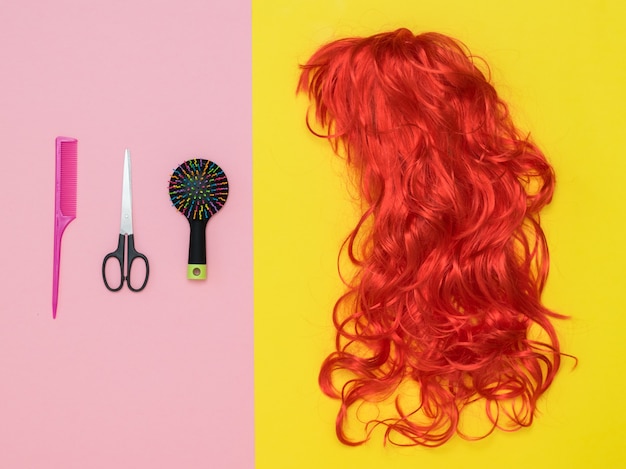 Bright wig, scissors and comb on a two-tone background. Lifestyle. Accessories to create style.