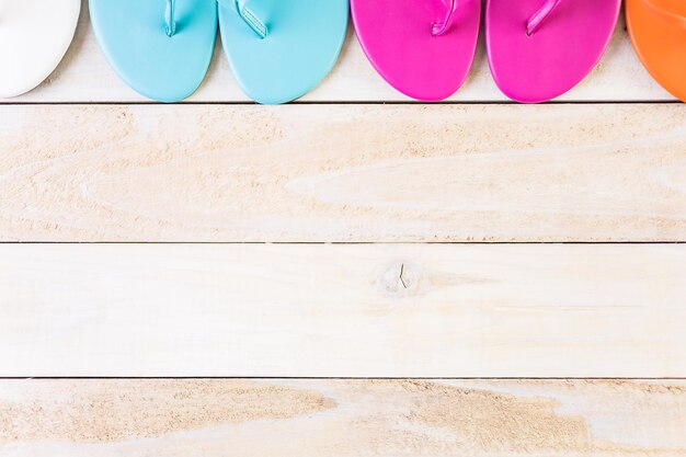 Photo bright women's flip flops on a wood board.