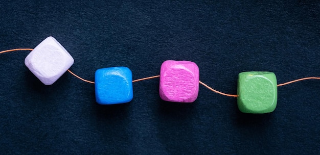 Bright wooden cube beads on thread macro