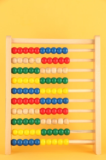 Photo bright wooden toy abacus, on yellow background