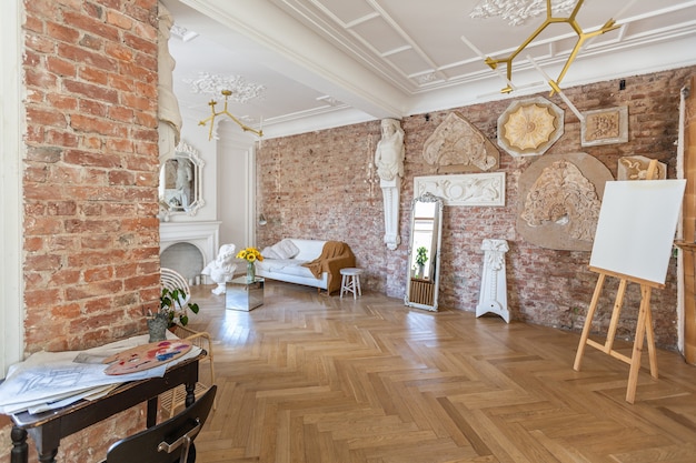 Bright workshop room for the creation and work of an architect and artist in a loft style with brick walls and parquet. the walls are decorated with examples of stucco.