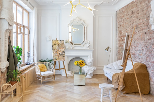 Foto luminosa sala laboratorio per la creazione e il lavoro di un architetto e artista in stile loft con pareti in mattoni e parquet. le pareti sono decorate con esempi di stucchi.