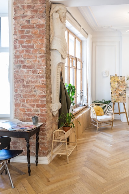 Bright workshop room for the creation and work of an architect and artist in a loft style with brick walls and parquet. the walls are decorated with examples of stucco.