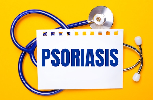 On a bright yellow background, a blue stethoscope and a sheet of paper with the text PSORIASIS. Medical concept