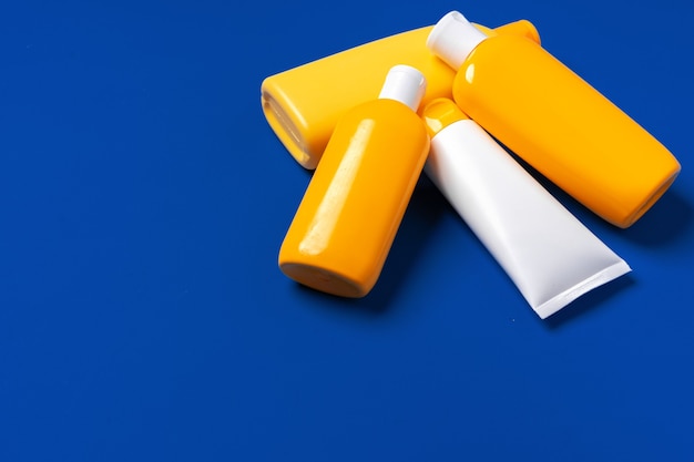 Фото Ярко-желтые бутылки солнцезащитного продукта на темно-синем бумажном фоне