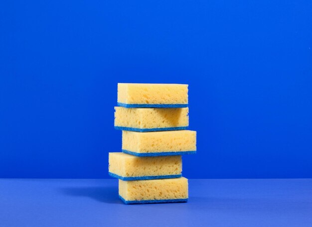 Bright yellow dishwashing sponges on a blue background