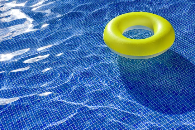 Bright yellow inflatable lifebuoy in an outdoor swimming pool