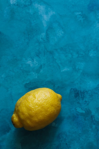 Bright yellow lemon on blue watercolor background