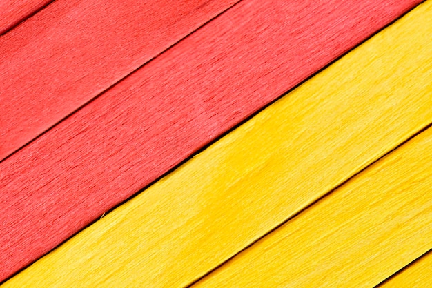 Bright yellow and red painted boards arranged diagonally. Close up wooden textured background.