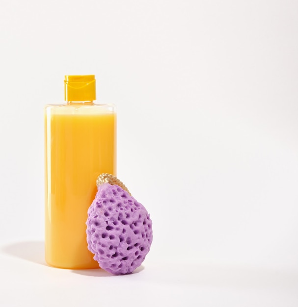 Bright yellow shower gel and purple porous shower sponge isolated on white background Copy space for text