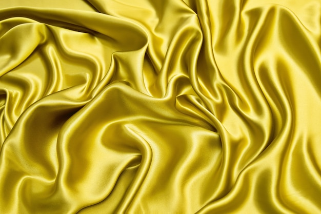 Bright yellow silk or satin fabric background with waves. Abstract pattern for design with copy space