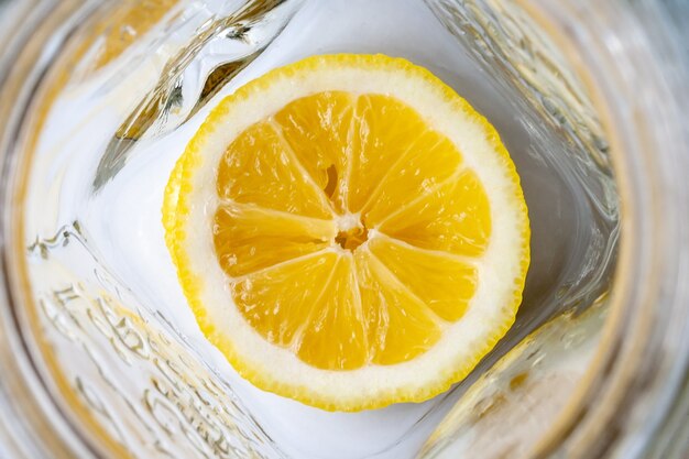 Bright yellow sliced lemon at the bottom of an empty glass mug. Lemonade ingredients for breakfast on a sunny morning. Selective focus. Top view