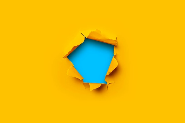 Bright yellow torn paper inside in a hole blue cardboard background.