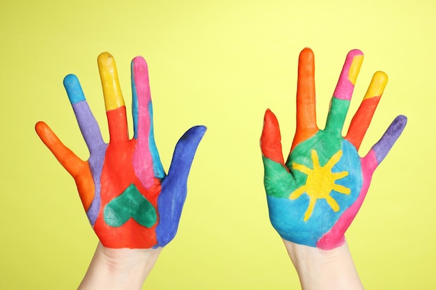 Brightly colored hands on green background closeup