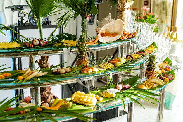 Brightly decorated buffet with different exotic fruits for guests outdoors. Assorted delicacies of exotic fruit, restaurant food at event.