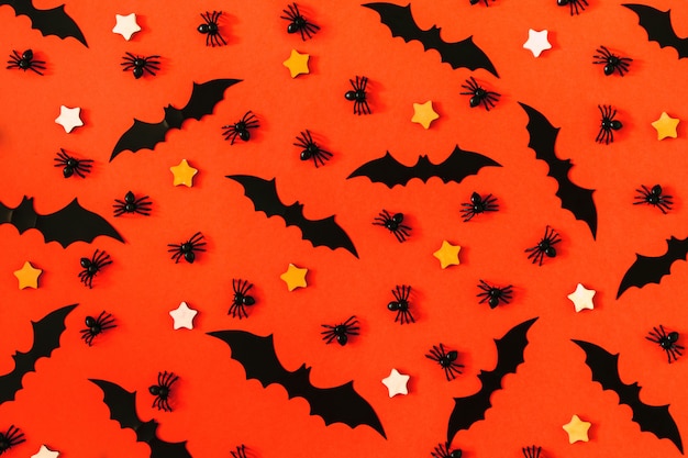 On a brightly orange surface, many decorative black spiders, bats.