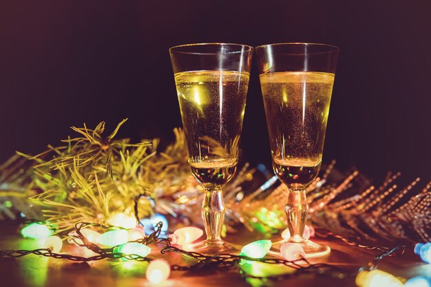 Bril tegen de achtergrond van een slinger. champagne drinken in een romantische setting. de viering van kerstmis en nieuwjaar samen.