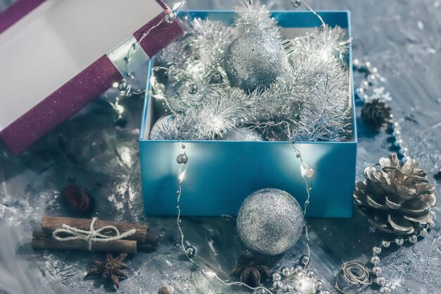 Briljante geschenkdoos met feestelijke decoraties binnen op een grijze achtergrond met lichtgevende lichten