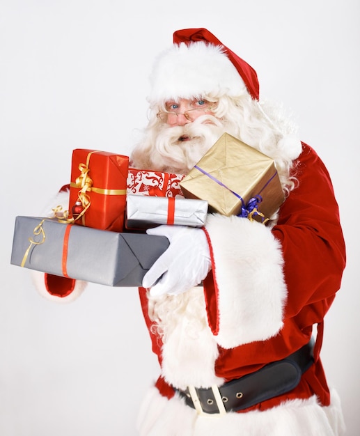 Bringing you some Christmas magic Santa Claus holding a pile of wrapped christmas gifts portrait