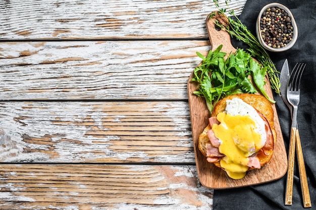 Brioche sandwich with bacon, egg Benedict and hollandaise sauce. White background. Top view. Copy space