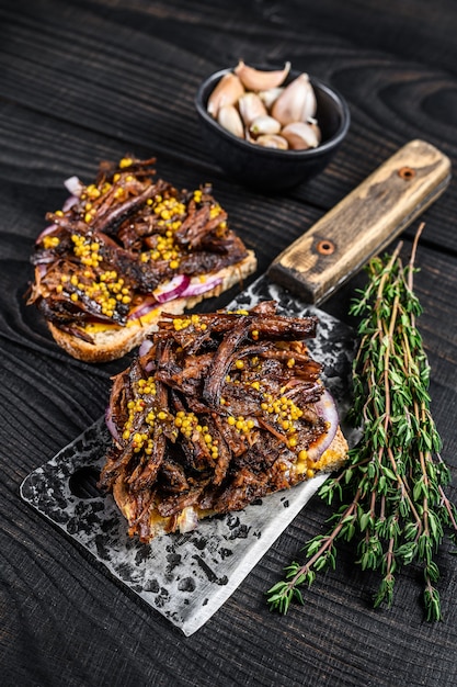 Brisket Sandwich met gerookt rundvlees op een vleesmes. Zwarte houten achtergrond. Bovenaanzicht.