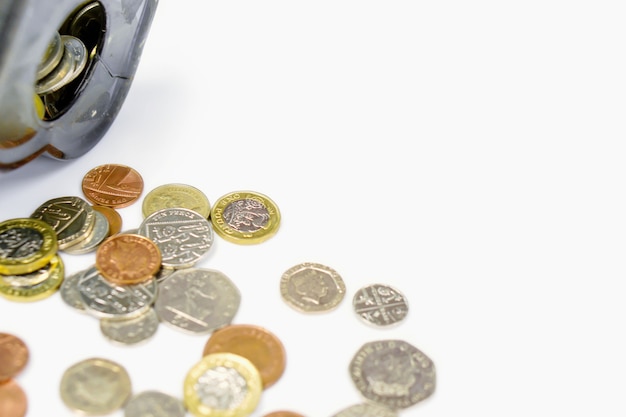 British currency coins open from the piggy bank laid out scattered on white background