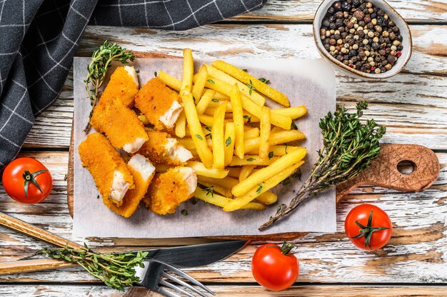 Pesce e patate fritte britannico sulla tavola di legno bianca.