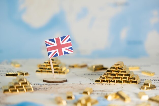 世界地図に描かれたイギリス国旗世界金融投資と英国の経済的地位を象徴する多数の金の棒に囲まれています