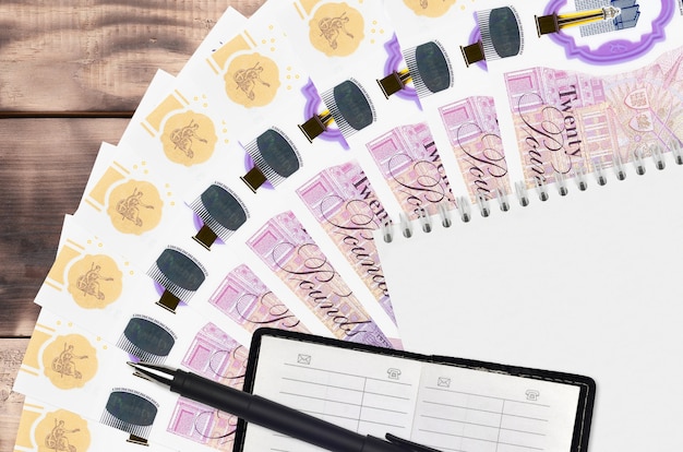 Фото Вентилятор банкнот британских фунтов и блокнот с контактной книгой и черной ручкой