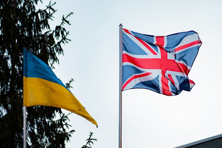 Britse en Oekraïense vlaggen tegen de achtergrond van blauwe lucht en sparren. Natuur. Relatie. Diplomatie. Politiek. Vriendschap. VK. Oekraïne. Bedrijf. Overeenkomst