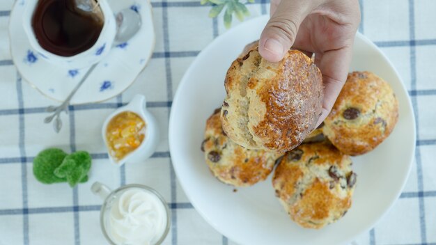 Britse scones met roomkaas, sinaasappeljam en een kopje koffie op blauw zegel tafelkleed. Zoom macro.