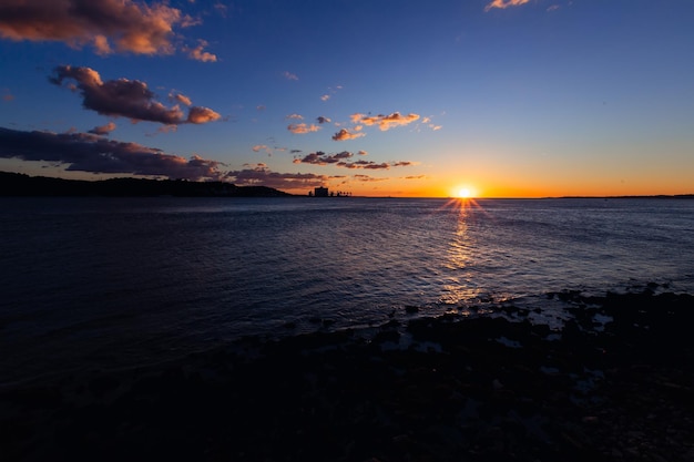 Broad Tagus river with the silhouettes of its shores and the sun