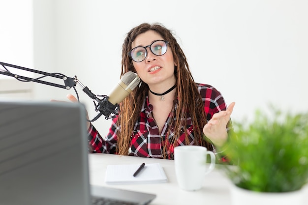 Trasmissione, musica, dj e concetto di persone - donna con dreadlocks e occhiali che lavorano alla radio.