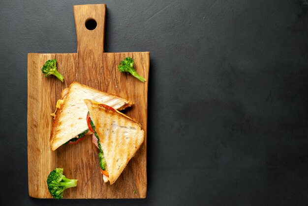 Broccoli cheese sandwiches on wooden cutting board, on concrete, slate background