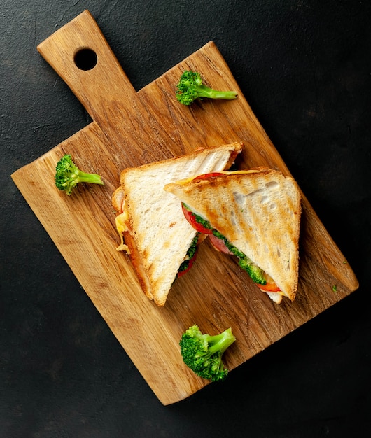 Бутерброды с сыром брокколи на деревянной разделочной доске, на бетоне, фоне шифера