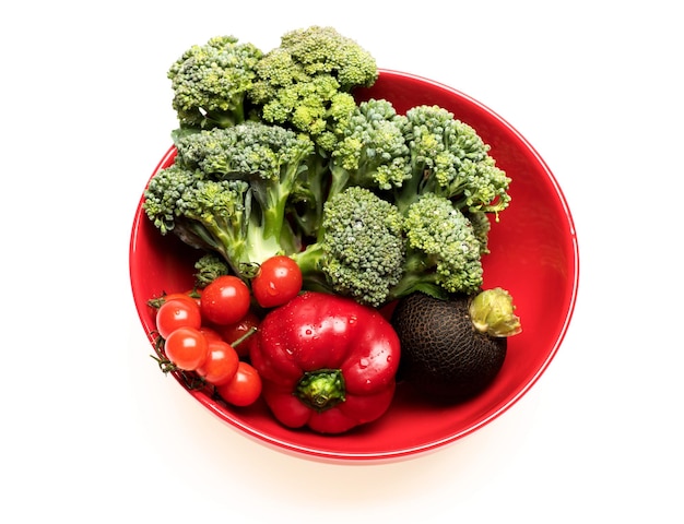 Broccoli cherry tomatoes black radish and peppers on plate Set of salad ingredients isolated on white background Cuisine and vegan diet concept Composition of fresh vegetables in red bowl