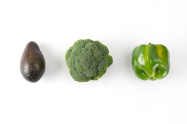 Broccoli, groene paprika, avocado. plantaardige creatieve lay-out op groene achtergrond