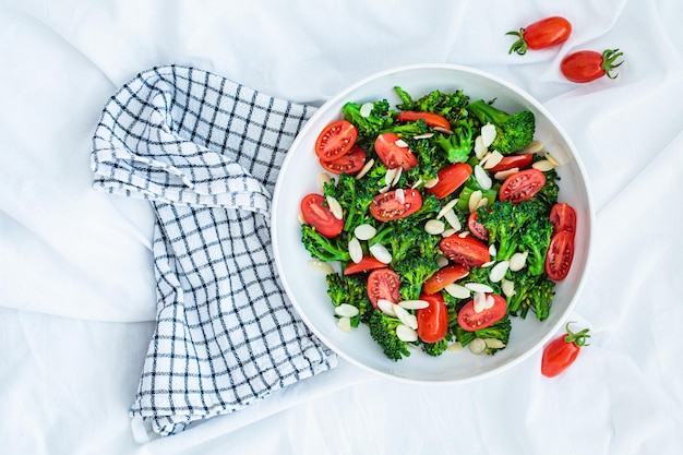 Insalata di broccoli con pomodorini e mandorle in ciotola bianca ricetta detox vegana