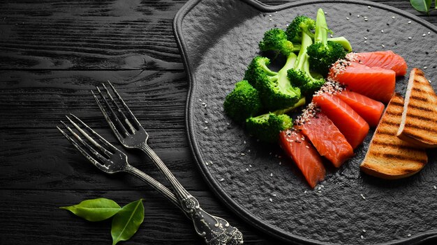 Broccoli and salted salmon fish Healthy Diet Food On a black stone plate Top view