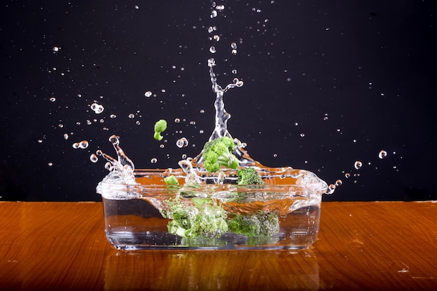 Foto broccoli valt in een kom water en zorgt voor een plons.