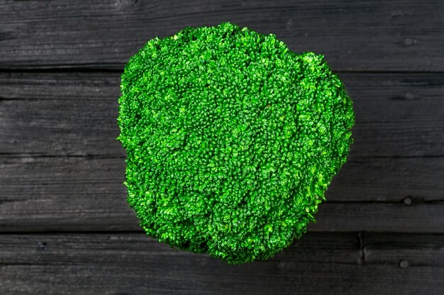 Broccoli in a wooden bowl on a black background old