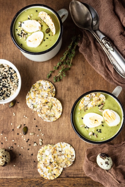 Broccolisoep met kwartelsei, crackers en zaadmix op een houten dienblad