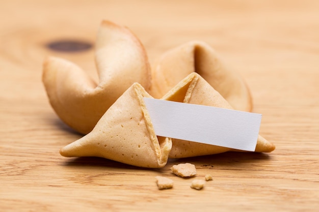 A brocken fortune cookie with note on wooden table background. Taken in Studio with a 5D mark III.