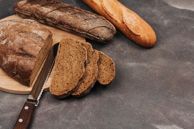 Broden van rogge en tarwebrood op een houten bord. sneetjes brood en mes.