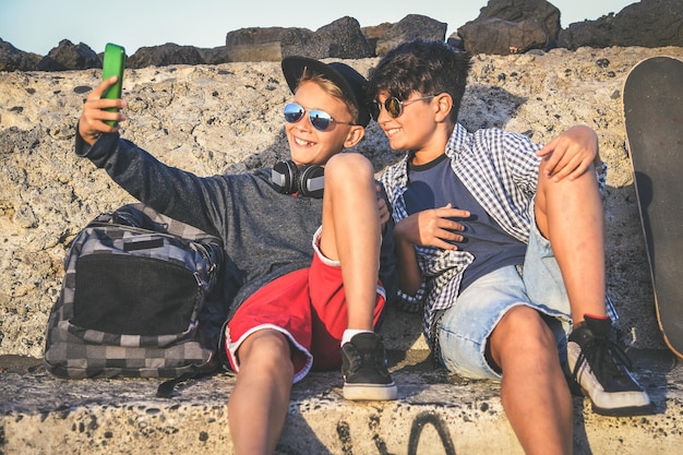 Broeders met hun mobiele telefoon terwijl ze op het strand zitten