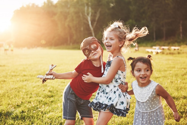 Broer en twee zussen spelen samen. Drie kinderen spelen met een houten vliegtuig buiten